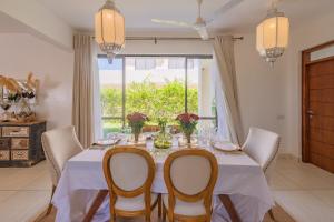 jadalnia ze stołem i krzesłami oraz oknem w obiekcie Kuza The Palm Villas at Vipingo w mieście Kilifi