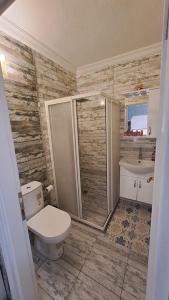 uma casa de banho com um WC, um chuveiro e um lavatório. em Denizkizi butik otel em Küçükkuyu