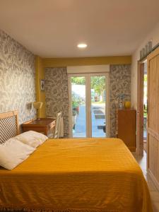 ein Schlafzimmer mit einem großen gelben Bett und einer Glasschiebetür in der Unterkunft Habitaciones Estrella del Norte in Santander