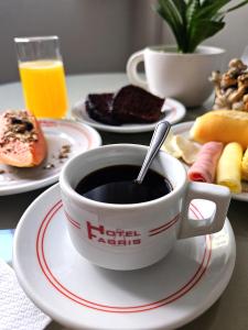 eine Tasse Kaffee auf einem Tisch mit Tellern. in der Unterkunft Hotel Fabris in Nova Friburgo