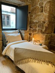 2 Betten in einem Zimmer mit einer Steinmauer in der Unterkunft Senhora da Estrela AL in Seia