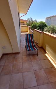 einen Balkon mit einem Stuhl auf einem Fliesenboden in der Unterkunft Casa Vacanze Sa Rocca Tunda- Putzu idu- sardegna in Putzu Idu