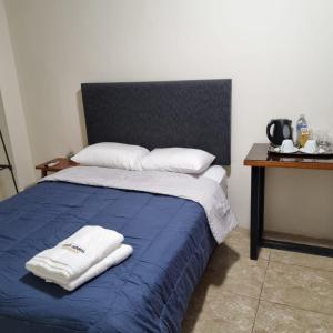 um quarto com uma cama azul com duas toalhas em Gran Imperial Avenida em Tumbes