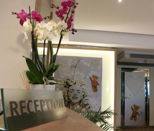 eine Vase mit Blumen auf einer Theke mit einem Schild in der Unterkunft Hôtel Victoria in Cannes