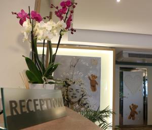 a vase of flowers on a counter with a sign at Hôtel Victoria in Cannes +37 photos