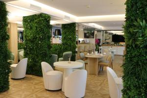 ein Restaurant mit weißen Tischen und Stühlen und einer grünen Wand in der Unterkunft Hôtel Victoria in Cannes