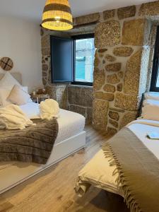 1 Schlafzimmer mit 2 Betten und einer Steinmauer in der Unterkunft Senhora da Estrela AL in Seia