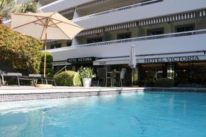 uma piscina com um guarda-sol e um hotel em Hôtel Victoria em Cannes