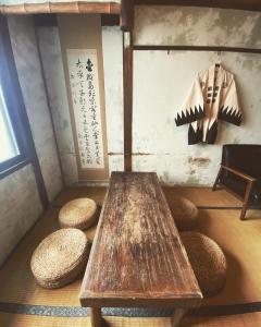 un tavolo in legno e sgabelli in una stanza con parete di Hostel Otro Mundo a Kyoto
