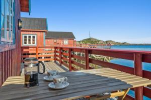 a wooden table with two cups of coffee on a balcony at Sjøhaug Rorbu, Fishcermanns cabin in Moskenes