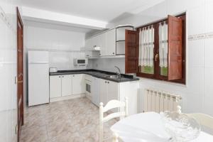 uma cozinha com armários brancos, uma mesa e um lavatório em Apartamentos el Acebo em Naves