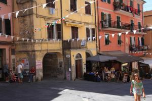 a woman walking down a street with flags and buildings at Fisherman's House in Riomaggiore