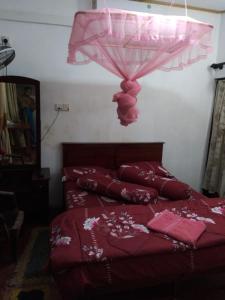1 dormitorio con cama roja y sombrilla rosa en Suriya Ocean Villa, en Wadduwa
