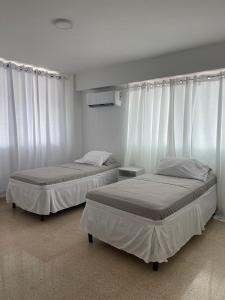 2 camas en una habitación con cortinas blancas en Habitaciones privadas en un departamento encantador, en Panamá