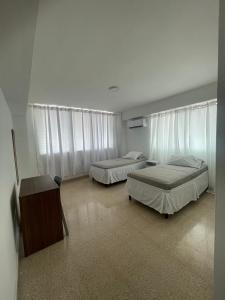 een slaapkamer met 2 bedden, een bureau en gordijnen bij Habitaciones privadas en un departamento encantador in Panama-Stad