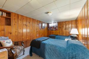 una camera da letto con pareti in legno, un letto e una sedia di The Chick Inn a Baker City
