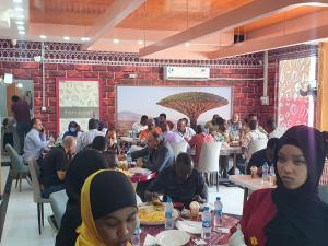 eine Gruppe von Personen, die in einem Restaurant an Tischen sitzen in der Unterkunft SIESTA HOTEL in Dschibuti