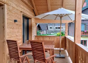 een houten tafel en stoelen met een parasol op een veranda bij Apartments Haufhof , Haus im Ennstal bei Schladming in Haus im Ennstal