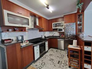 a kitchen with wooden cabinets and a tv on the wall at Apartamento Xanela o Mar in Laxe