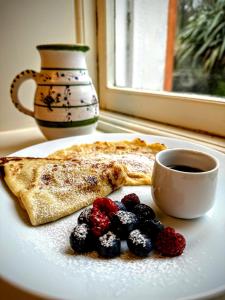 a plate with a slice of pizza with berries and a cup of coffee at Clone Country House in Aughrim