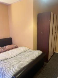 a bedroom with a bed and a wooden cabinet at White and Sandstone Astley Bridg in Bolton