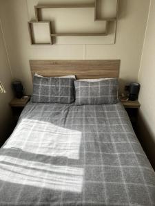 ein Bett mit einer karierten Decke und 2 Kissen in der Unterkunft MOONSTONE Lymington in Leysdown-on-Sea