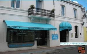 un magasin avec un auvent bleu devant un bâtiment dans l'établissement Hotel Phoebus, à La Tremblade
