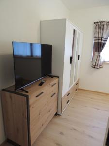 a living room with a flat screen tv on a wooden dresser at Bacher´s Home am Sonnenplateau in Mieming