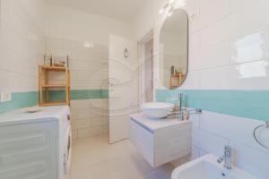 Un baño blanco con lavabo y espejo. en Appartamento Le Conchiglie - Goelba, en Portoferraio