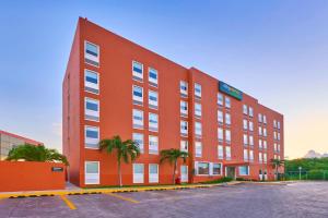 a red building with palm trees in a parking lot at City Express Junior by Marriott Tijuana Otay in Tijuana