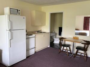 uma cozinha com um frigorífico branco e uma mesa com cadeiras em The Fort Nashwaak Motel em Fredericton