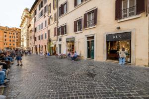 a cobblestone street with a crowd of people walking down the street at Luxury Apartments Pantheon Roma in Rome