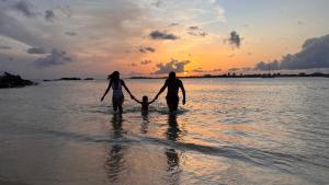 two adults and a child walking in the water on the beach at Simpson Bay Resort Marina & Spa in Simpson Bay