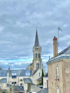 eine Kirche mit einem Turm mit einer Uhr drauf in der Unterkunft Chaleureuse Échappée : Commodités, Calme, Confort in Angers