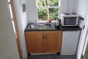a kitchen with a microwave and a sink and a window at Southcote Accommodation in Tintagel