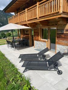 um alpendre de uma cabana de madeira com cadeiras e um guarda-sol em Chalet - Das Schrofen em Ramsau im Zillertal