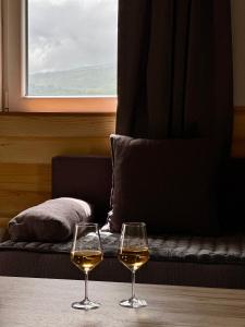 zwei Gläser Weißwein auf einem Tisch mit einer Couch in der Unterkunft Rural Resort Tron in Plužine