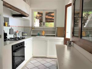 a kitchen with white cabinets and a stove top oven at Villa A Madonnuzza - casa sul mare, splendide terrazze panoramiche in Lingua