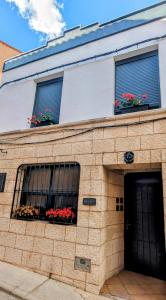 ein Gebäude mit zwei Fenstern mit Blumen darauf in der Unterkunft Alojamiento 13 Jotas in Iniesta