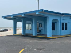 加爾維斯敦的住宿－Econo Lodge Galveston Seawall，海滩旁的蓝色建筑,有车