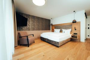 a bedroom with a large white bed and a chair at Hotel Tradizio in Mittelberg
