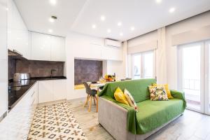 a living room with a green couch and a kitchen at Apartment Carvoeiro By The Sea 1 by Algarve Vacation in Carvoeiro