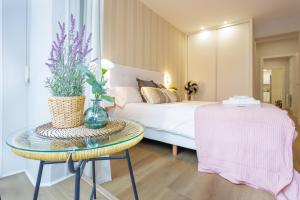 ein Schlafzimmer mit einem Bett und einem Tisch mit einer Vase in der Unterkunft Apartamento Pagasarri, Bilbaohost in Bilbao