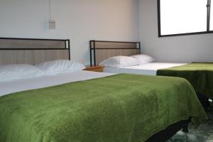 2 camas en una habitación con sábanas verdes en Aparta Suite Torre De Prado Penthouse, en Medellín