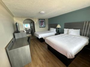 a hotel room with two beds and a television at Econo Lodge Galveston Seawall in Galveston