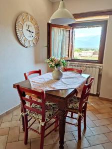 a dining room table with chairs and a clock on the wall at Il Bagolaro Casa Vacanze in Sulmona