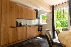 una cocina con armarios de madera y una mesa con sillas. en Holiday Home Eekhoornbosch en Otterlo