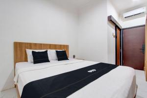 a bedroom with a large bed with black and white sheets at Capital O 93266 Palmier Hotel in Yogyakarta