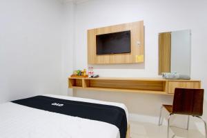 a room with a bed and a tv on a wall at Capital O 93266 Palmier Hotel in Yogyakarta