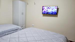 1 dormitorio con 1 cama y TV en la pared en Departamento Capital en San Fernando del Valle de Catamarca